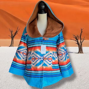 May include: A hooded coat with a Southwestern-inspired design. The coat features a turquoise blue base with horizontal stripes and geometric patterns in orange, white, and blue. The hood and collar are lined with a brown, soft material. The coat has wooden toggle closures.