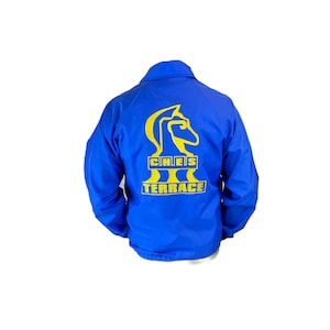 Puede incluir: Una chaqueta azul real con un logotipo de caballero amarillo y el texto "CHIEFS TERRACE" en la espalda.