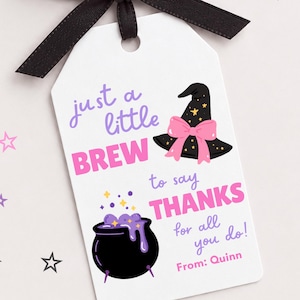 Può includere: Un'etichetta regalo rettangolare bianca con un fiocco di nastro nero sulla parte superiore. L'etichetta presenta un cappello da strega nero con un fiocco rosa, un calderone nero con liquido viola e il testo: just a little BREW to say THANKS for all you do! From: Quinn.