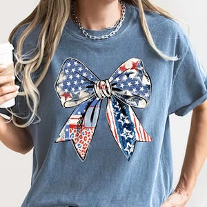 Distressed patriotic bow graphic in red white and blue with stars stripes and mixed animal print patterns perfect for USA 4th of July shirts women’s Independence Day tees America flag summer outfits cute freedom celebration apparel or red white blue patriotic shirt for parades BBQs and holiday events