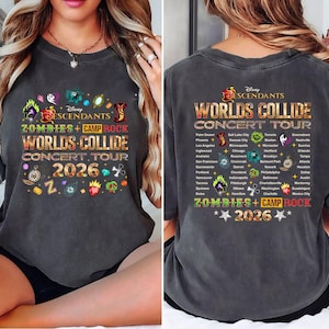 May include: Dark gray t-shirt featuring the text "Disney Descendants Zombies + Camp Rock Worlds Collide Concert Tour 2026" in colorful lettering. The shirt has a crew neck and short sleeves. The back of the shirt lists tour cities.