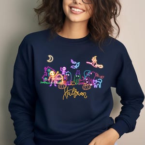 Spooky neon Halloween shirt with glow-in the dark designs of skeletons, ghosts, and a flying witch, great for Halloween parties and festive outings.