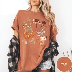 retro disney halloween shirt design featuring coquette bow mickey ears pumpkins fall leaves cozy autumn coffee cup tis the season beaded necklace and cute disney fall vibes illustration