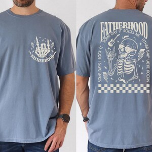 Funny Fatherhood shirt featuring rock and roll skeleton hand with sunglasses and lightning bolts, bold graphic tee for dads who love music, cool retro Father's Day shirt for first-time dad or new dad, punk dad gift t-shirt with skeleton design, Father's Day gift for husband from kids, edgy and fun dad shirt with vintage rock band vibe, fatherhood rocks themed tee for dad’s birthday or family photos