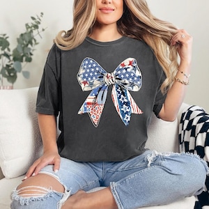 Distressed patriotic bow graphic in red white and blue with stars stripes and mixed animal print patterns perfect for USA 4th of July shirts women’s Independence Day tees America flag summer outfits cute freedom celebration apparel or red white blue patriotic shirt for parades BBQs and holiday events