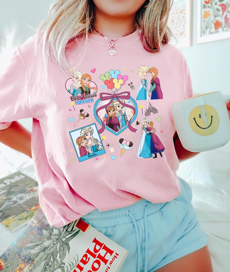 Cute coquette-style Disney Frozen shirt featuring Elsa and Anna with hearts, bows, and pastel icons, ideal for sisters and best friends.