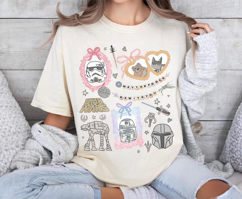 Retro pastel water color coquette Star Wars shirt with kawaii-style Stormtrooper, R2D2, AT-AT, Ewok, and Mandalorian helmet in watercolor frames with bows and hearts, perfect for Disney trip or Star Wars Day outfit.