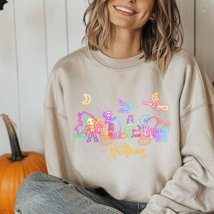 Spooky neon Halloween party shirt with glow in the dark skeletons, ghosts, and a witch, a fun and eerie design for trick or treating or festive celebrations.