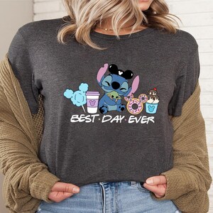 Stitch Best Day Ever Shirt featuring Stitch hugging Baby Yoda, surrounded by colorful Disney snacks like Mickey-shaped donuts, cotton candy, ice cream, and a Disney coffee cup. Cute and fun design perfect for a Disney Snacks Sweatshirt or T-shirt, great for Disney park trips, foodie gifts, and Stitch fans.
