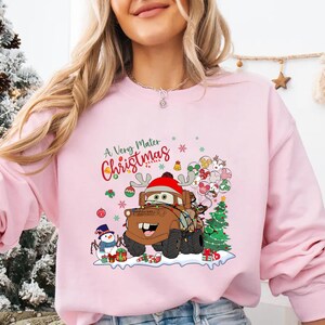 Cute Disney Cars Christmas shirt with Mater in holiday cheer, surrounded by lights and festive elements, perfect for Disney trips or holiday wear.
