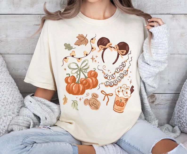 retro disney halloween shirt design featuring coquette bow mickey ears pumpkins fall leaves cozy autumn coffee cup tis the season beaded necklace and cute disney fall vibes illustration