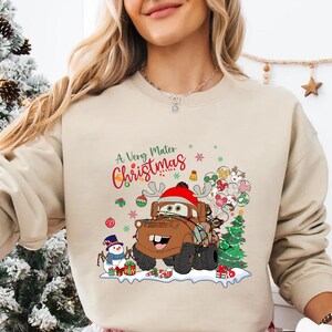 A Very Mater Christmas design featuring Mater with reindeer antlers, Christmas tree, and snowman, ideal for Disney Cars fans and holiday fun.