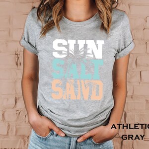 Bold beach-themed graphic with the words 'Sun Salt Sand' in large block letters, featuring palm trees and coastal colors—perfect for summer vacation or beach day t-shirts.