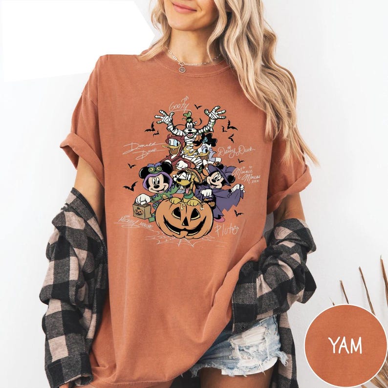 Retro-style Halloween design featuring Mickey Mouse, Minnie, Goofy, Donald, Daisy, and Pluto in costumes around a large jack-o'-lantern with bats and spiderwebs. Perfect for Disney Halloween party trips and fall-themed outfits.