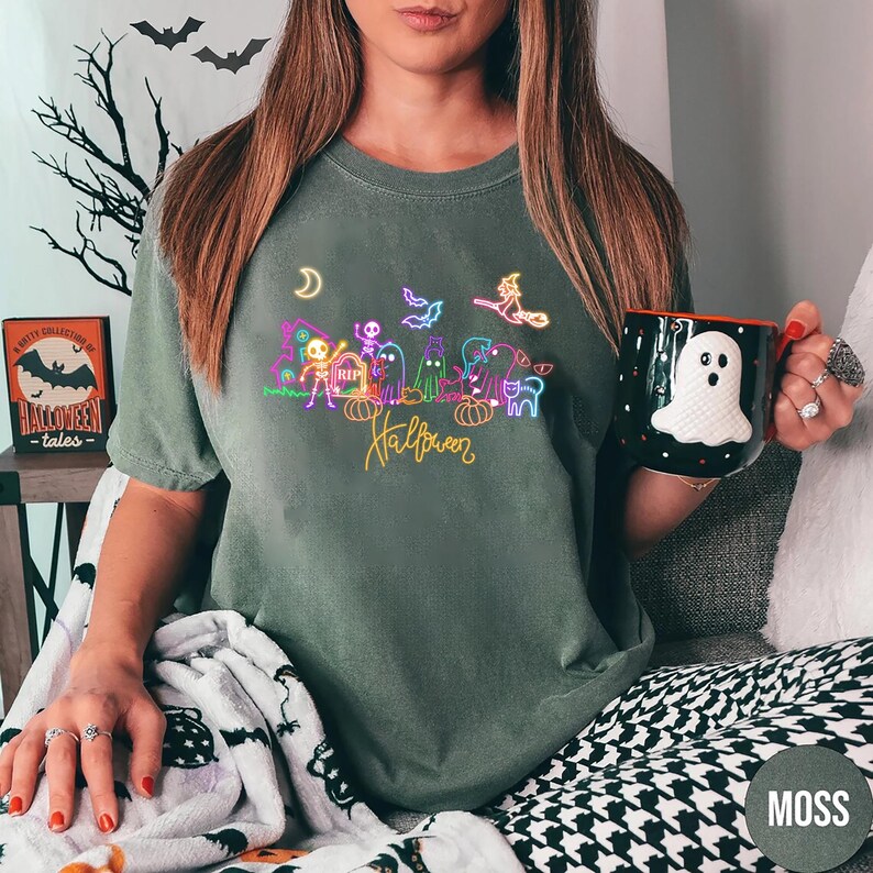 Glow in the dark Halloween shirt featuring neon skeletons, ghosts, and a witch design, perfect for making a spooky statement at Halloween events.