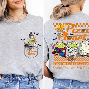 Toy Story Pizza Planet Halloween shirt front design with three green aliens dressed as devil mummy and ghost holding candy, featuring vintage Disney Halloween style for Not So Scary Party or Disneyland trip. Pizza Planet Halloween claw machine pocket design on the back of shirt with Toy Story aliens in costumes and spooky spiderweb, perfect for Disney family matching Halloween outfit and Mickey’s Not So Scary event.