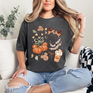 retro disney halloween shirt design featuring coquette bow mickey ears pumpkins fall leaves cozy autumn coffee cup tis the season beaded necklace and cute disney fall vibes illustration