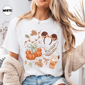retro disney halloween shirt design featuring coquette bow mickey ears pumpkins fall leaves cozy autumn coffee cup tis the season beaded necklace and cute disney fall vibes illustration