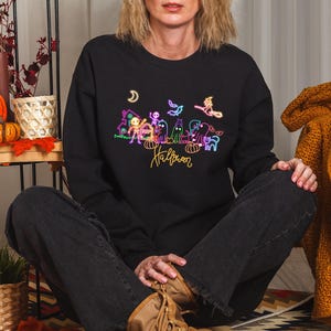 Glow-in-the-dark Halloween graphic tee showcasing neon spooky skeletons, playful ghosts, and a witch, ideal for Halloween events and trick-or-treating.