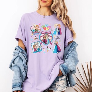 Cute coquette-style Disney Frozen shirt featuring Elsa and Anna with hearts, bows, and pastel icons, ideal for sisters and best friends.