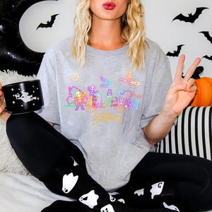 Neon Halloween glow in-the dark tee with eerie skeletons, playful ghosts, and a witch, ideal for Halloween parties or trick-or-treating fun.
