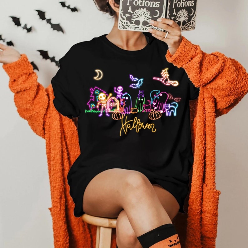 Neon Halloween shirt featuring glow-in-the-dark skeletons, ghosts, and a witch, perfect for spooky parties and Halloween celebrations.