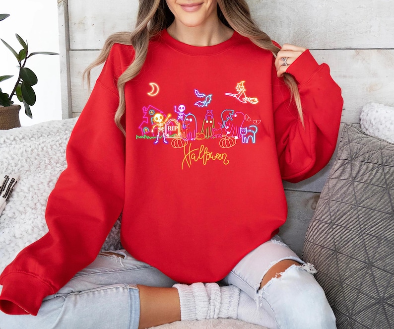 Fun glow in the-dark Halloween shirt with neon skeletons, spooky ghosts, and a witch design, perfect for trick-or-treating and Halloween festivities.