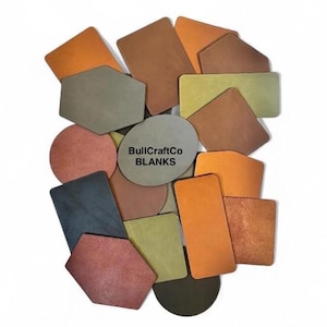 May include: A collection of leather blanks in various shapes and colors, including orange, brown, green, and gray. The text "BullCraftCo BLANKS" is printed on a gray oval-shaped blank.