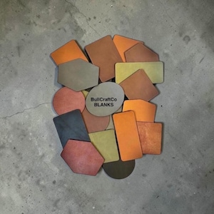 May include: A collection of various shaped blanks in shades of orange, brown, yellow, and gray. The shapes include rectangles, circles, and irregular polygons. The text "BullCraftCo BLANKS" is printed on a circular blank.