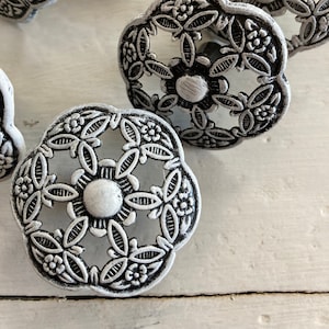 Peut inclure: Ensemble de six poignées de tiroir en métal argenté avec un motif floral. Les poignées ont une finition vieillie et sont parfaites pour ajouter une touche de charme vintage à n'importe quelle maison.