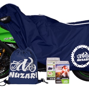 May include: A blue motorcycle cover with white stitching and a white logo that says "Nuzari" on the side. The cover is on a green motorcycle. There is a blue drawstring bag with the same logo and two boxes that say "Maxx Plus" on them.