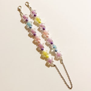 May include: Two pastel colored star-shaped beaded chains with silver clasps and a silver chain connector. The beads are translucent and have a speckled appearance.