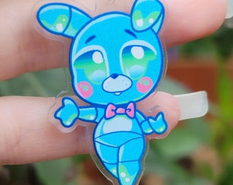 May include: A blue cartoon bunny charm with a pink bow tie and rosy cheeks. The charm has a clear outline and is attached to a black cord with a silver-colored clasp. The bunny has large, expressive eyes.