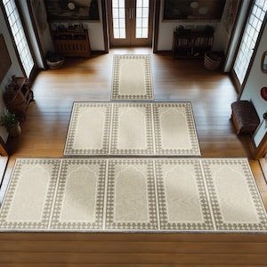 May include: A set of five beige prayer rugs with brown borders and intricate patterns. The rugs are arranged in a hallway with wooden floors.