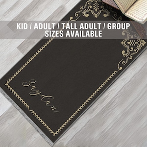 May include: A black prayer rug with a gold border and intricate gold designs. The rug has the word "Saydan" written in gold script. The text "KID / ADULT / TALL ADULT / GROUP SIZES AVAILABLE" is written in white on a black background.