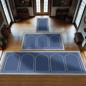 May include: Three blue prayer rugs with white trim and arched designs. The rugs are arranged in a hallway with wooden floors.