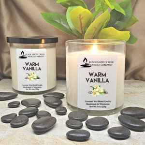 Pu&ograve; includere: Due barattoli di vetro di candele a base di miscela di cera di cocco profumate alla vaniglia calda. Le candele sono realizzate a mano nel Wisconsin e hanno un peso netto di 8 once o 226 grammi. Le candele sono su una superficie bianca con ciottoli neri.