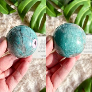 May include: A green amazonite sphere with a smooth, polished surface. The sphere is approximately 2 inches in diameter and has a light green color with darker green veins.