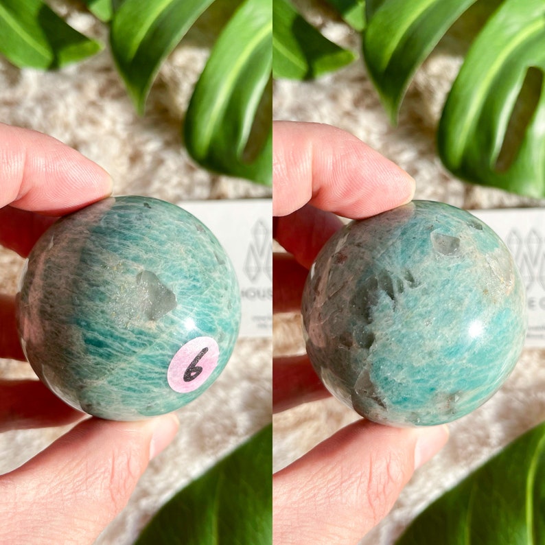 May include: A green and white amazonite sphere with a smooth, polished surface. The sphere is approximately 2 inches in diameter.
