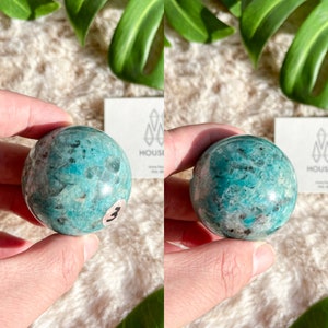 May include: A green and blue amazonite sphere with a smooth, polished surface. The sphere is approximately 2 inches in diameter.