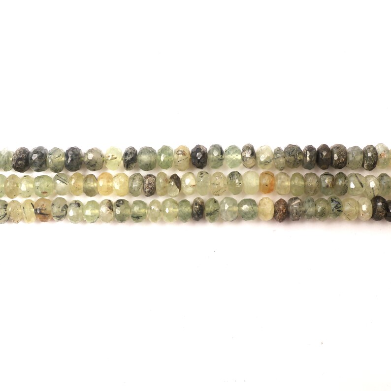 May include: A strand of green, brown, and clear faceted gemstone beads. The beads are round and have a slightly irregular shape.