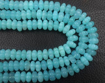 May include: Strands of light blue gemstone beads. The beads are oval-shaped with carved details, strung together to form multiple rows. The beads have a smooth, polished appearance and a consistent color throughout.