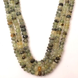 May include: A strand of green and brown faceted gemstone beads. The beads are strung on a clear thread and are approximately 6mm in diameter.