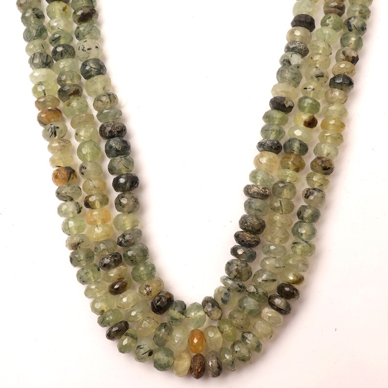 May include: A strand of green and brown faceted gemstone beads. The beads are strung on a clear thread and are approximately 6mm in diameter.