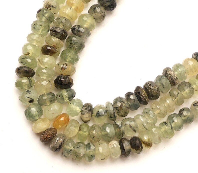 May include: A strand of green, black and yellow gemstone beads. The beads are faceted and have a rough, natural look.