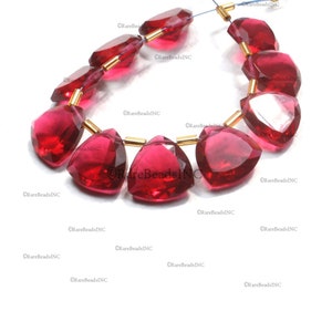 May include: A strand of faceted, deep red, triangular-shaped beads separated by small, cylindrical gold-toned metal spacers. The beads are translucent and arranged in a curved line, with the text RareBeadsINC visible multiple times.