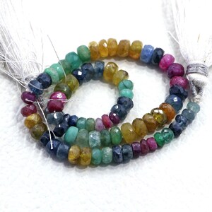 May include: A strand of faceted gemstone beads in various colors, including green, blue, yellow, and red. The beads are strung on a clear thread and have a polished finish.