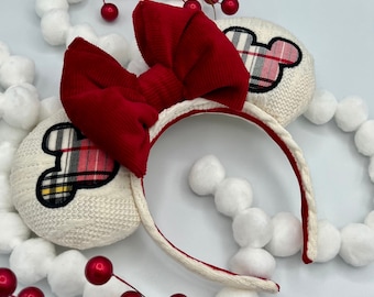 May include: White headband with red velvet bow and plaid Mickey Mouse ears. The headband is decorated with white pom-poms.