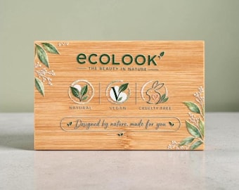 Puede incluir: Una caja rectangular de bambú con el texto verde ECOLOOK THE BEAUTY IN NATURE. Muestra tres iconos circulares que indican natural, vegano y libre de crueldad, con un gráfico de conejo y el texto Designed by nature, made for you.