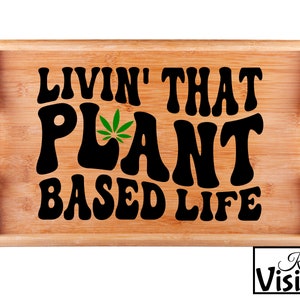 May include: A wooden serving tray with the text "Livin' That Plant Based Life" in black lettering with a green marijuana leaf graphic.